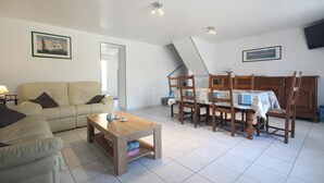 Ein Wohnzimmer mit einer Couch, einem Couchtisch und einem Esstisch mit Stühlen.