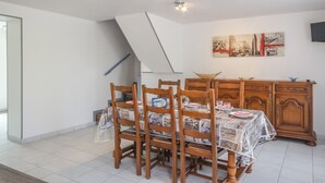 Ein Essbereich mit Holztisch und -stühlen, einem Holzschrank und einem an der Wand hängenden Gemälde.
