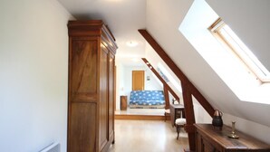 Ein schmaler Flur mit einem Holzkasten, einem kleinen Tisch mit einer Vase und einem Oberlicht.