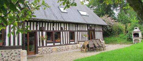 A traditional half-timbered house with a gravel driveway and outdoor seating area.