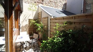 En terrasse med bord og stole, omgivet af et træhegn og planter.