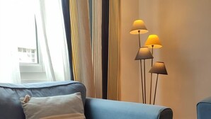 En moderne stue med en blå sofa, en stribet pude og en gulvlampe med tre lys.