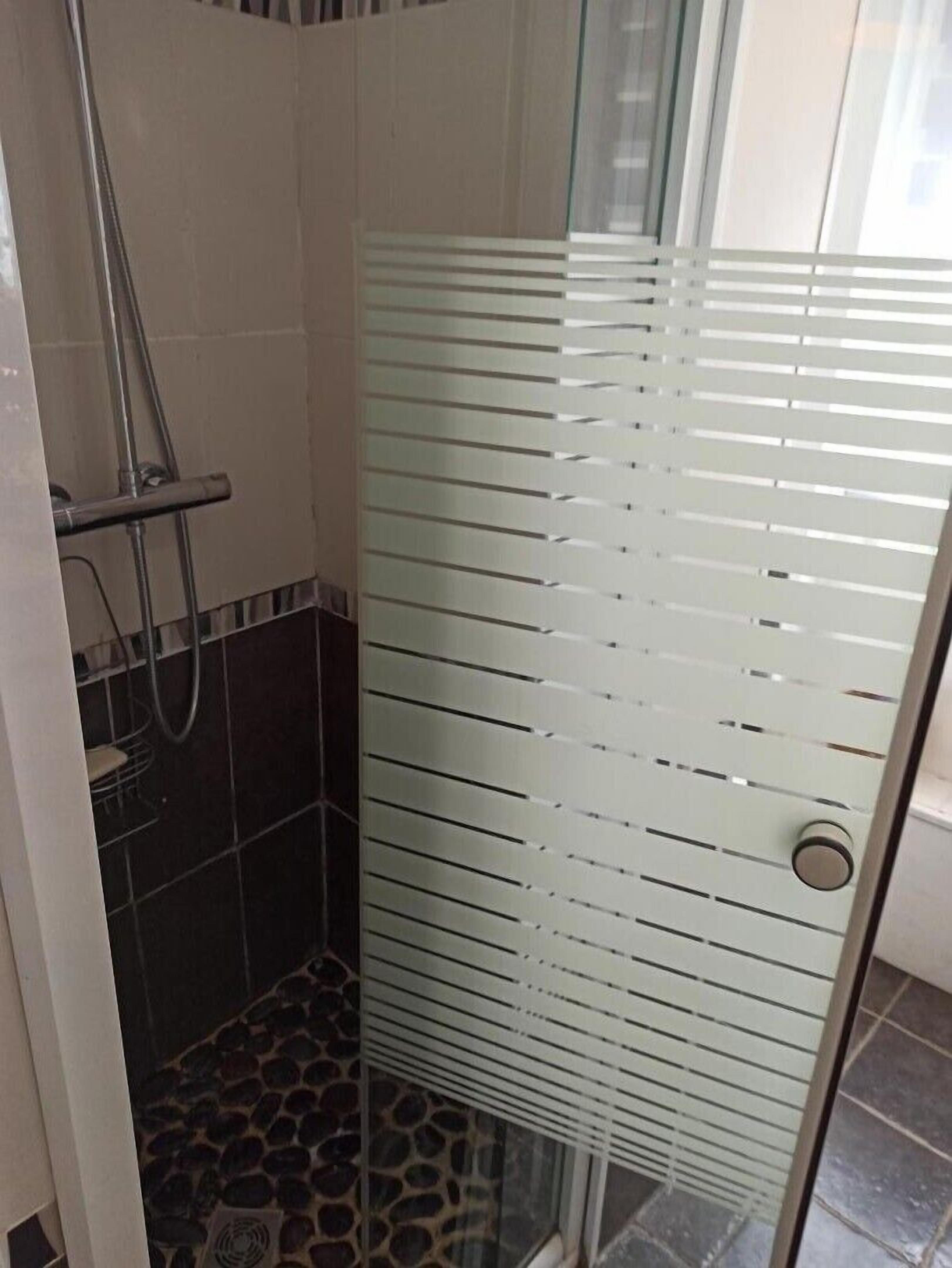 A glass-enclosed shower area with a tiled floor and a metal showerhead.