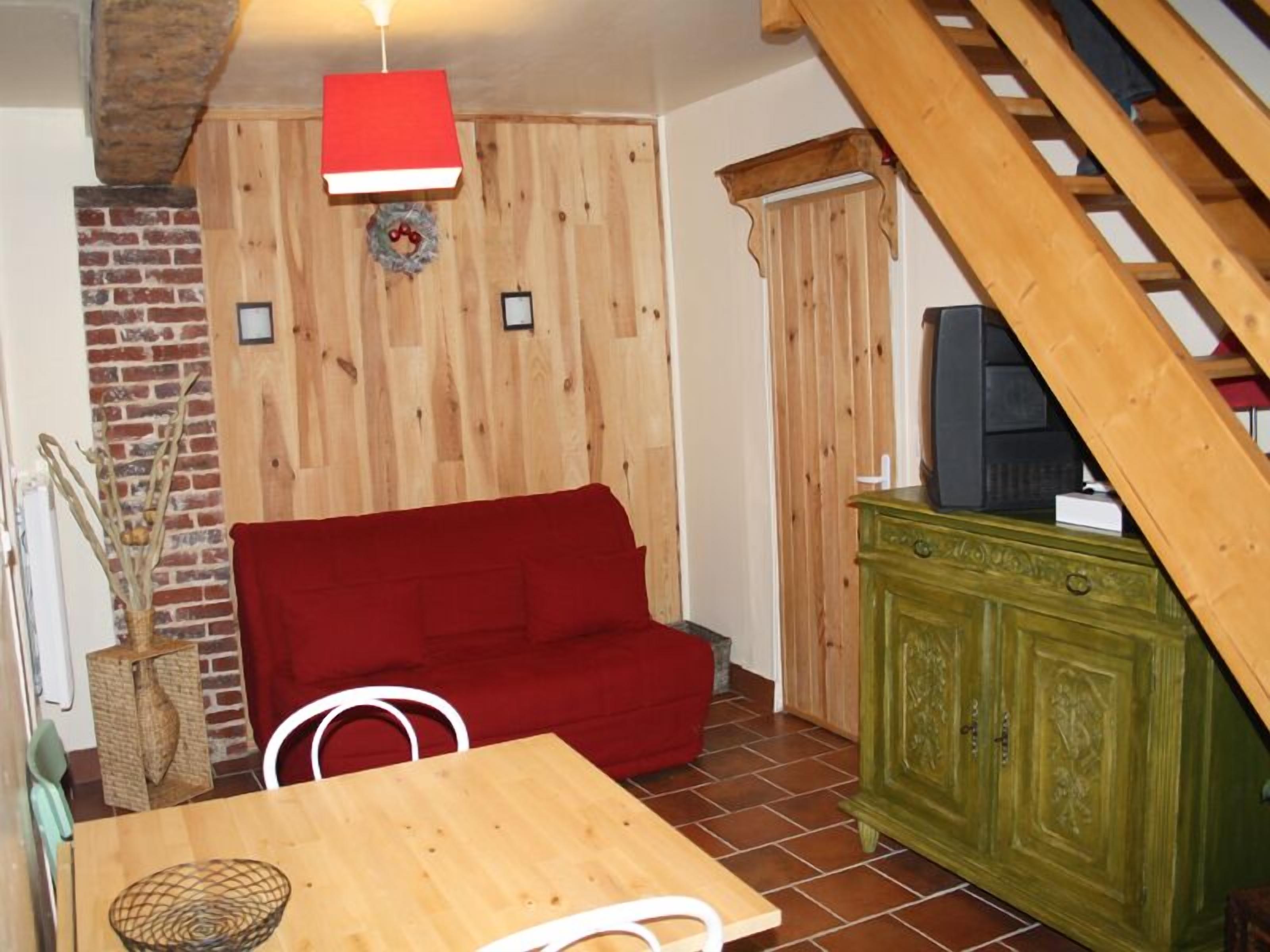 A cozy room with a red sofa, wooden walls, a green cabinet, and a television.