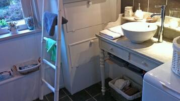 Un baño pequeño con lavamanos blanco, un espejo y una ventana.