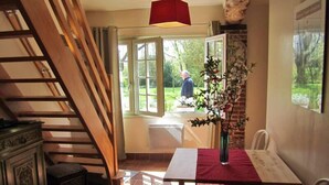 A dining area with a table, chairs, a vase with flowers, and a staircase. - La Cécilève - Riville (RIVILLE)