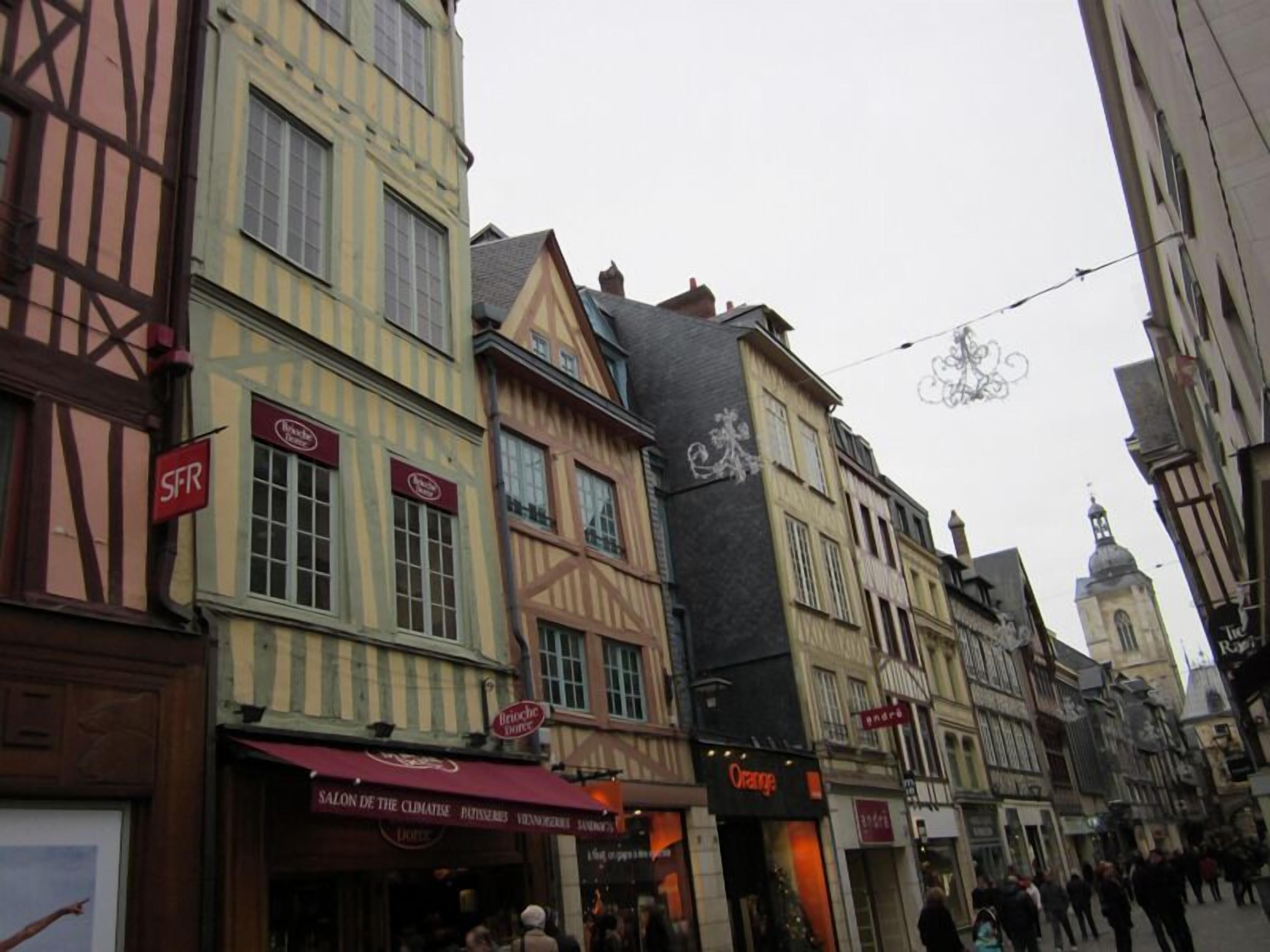 A street with traditional European architecture, including half-timbered buildings and a variety of storefronts.