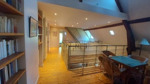 A loft-style room with wooden floors, a mezzanine level, and a staircase.
