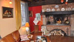 A cozy living room with a leather sofa, a fireplace, and a table with magazines. - Le Verger - Varneville Bretteville (VARNEVILLE BRETTEVILLE)