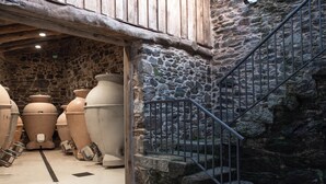 Ein Innenraum mit Steinwänden, großen Keramikvasen und einer Metalltreppe.