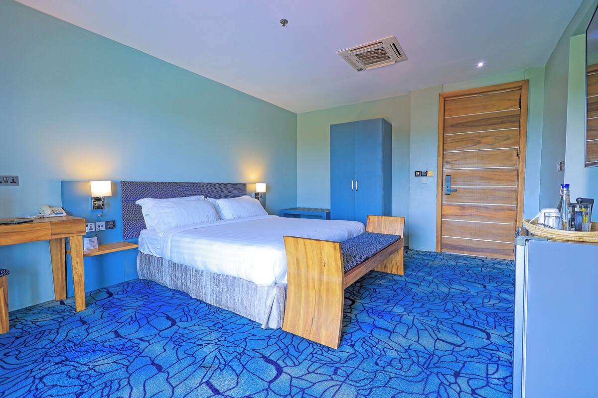 Ein Hotelzimmer mit Bett, Nachttischen, einem Kleiderschrank und einem Schreibtisch.