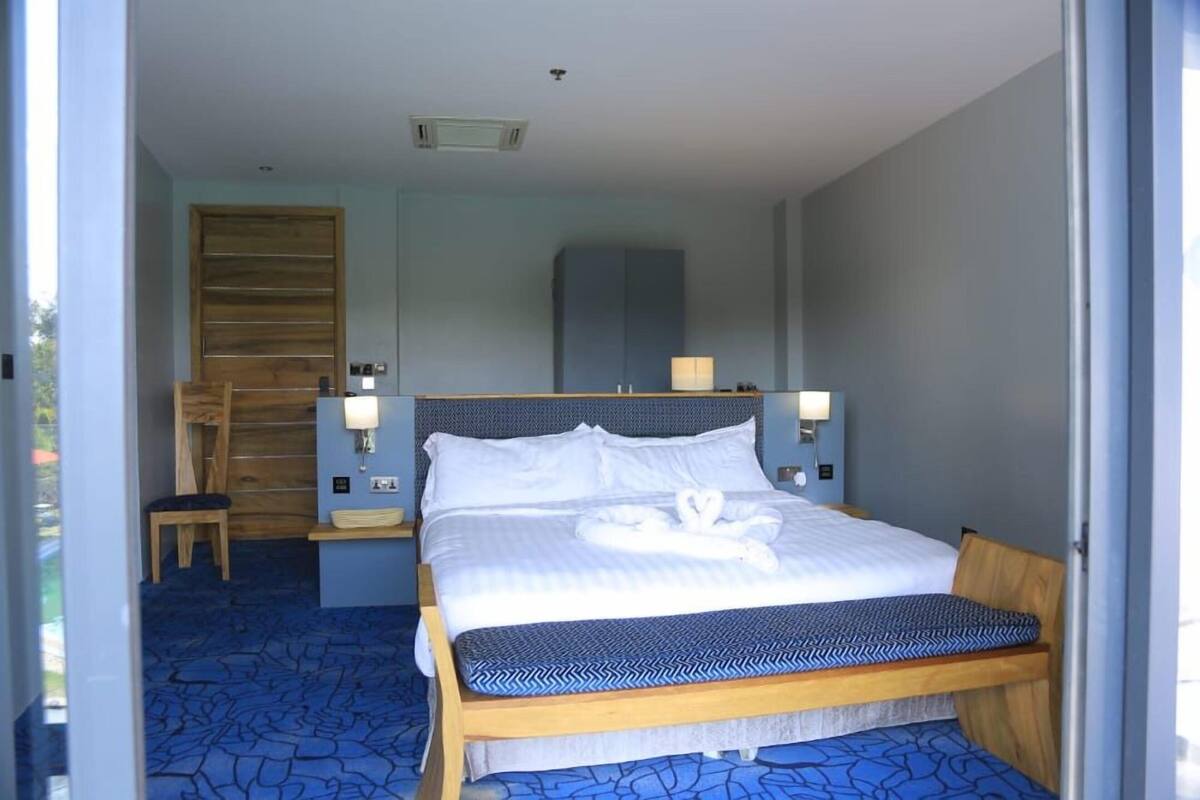 Ein Hotelzimmer mit einem Bett, Nachttischen, einer Bank, einem Holzschrank und einer Wandlampe.