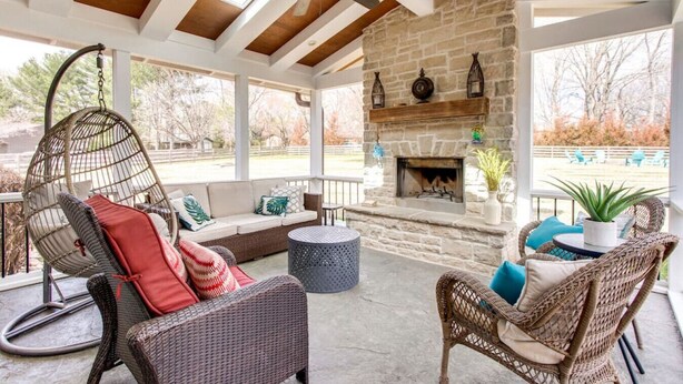 A covered outdoor seating area with wicker furniture, a stone fireplace, and a ceiling fan. - Private Hot Tub, Porch Fireplace, Large Yard (Franklin)