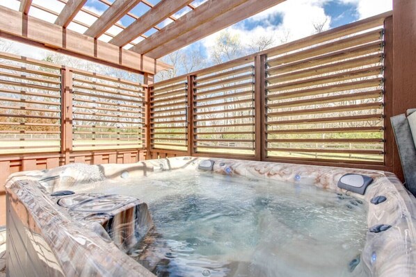 A hot tub with a wooden pergola structure and a view of the outdoors. - Private Hot Tub, Porch Fireplace, Large Yard (Franklin)