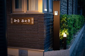 A building facade with a sign indicating "NISHISHICHIJI" and a small illuminated sign on the right. - Oyado Nishishichijo (Kyoto)