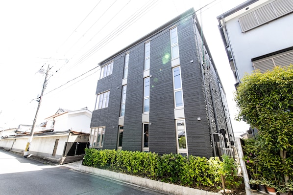 Un edificio moderno de dos plantas con fachada oscura y múltiples ventanales.