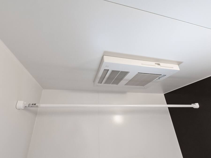 A white ceiling with a white air conditioning unit and a white towel rack.