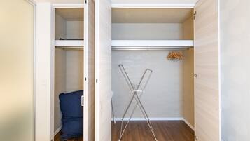 A walk-in closet with a hanging rod, a folding chair, and a blue chair.