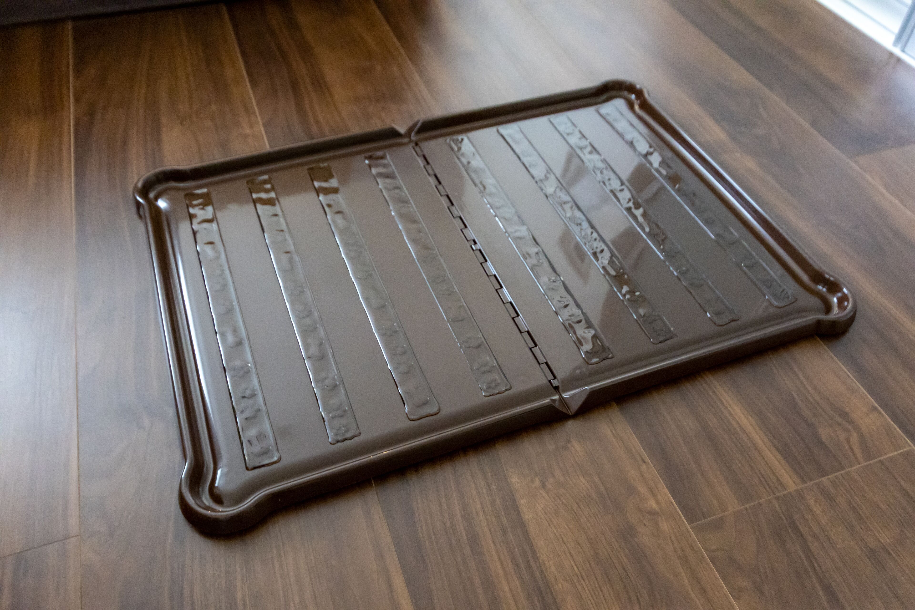 A metal tray with a reflective surface on a wooden floor.
