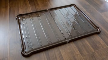 A metal tray with a reflective surface on a wooden floor.