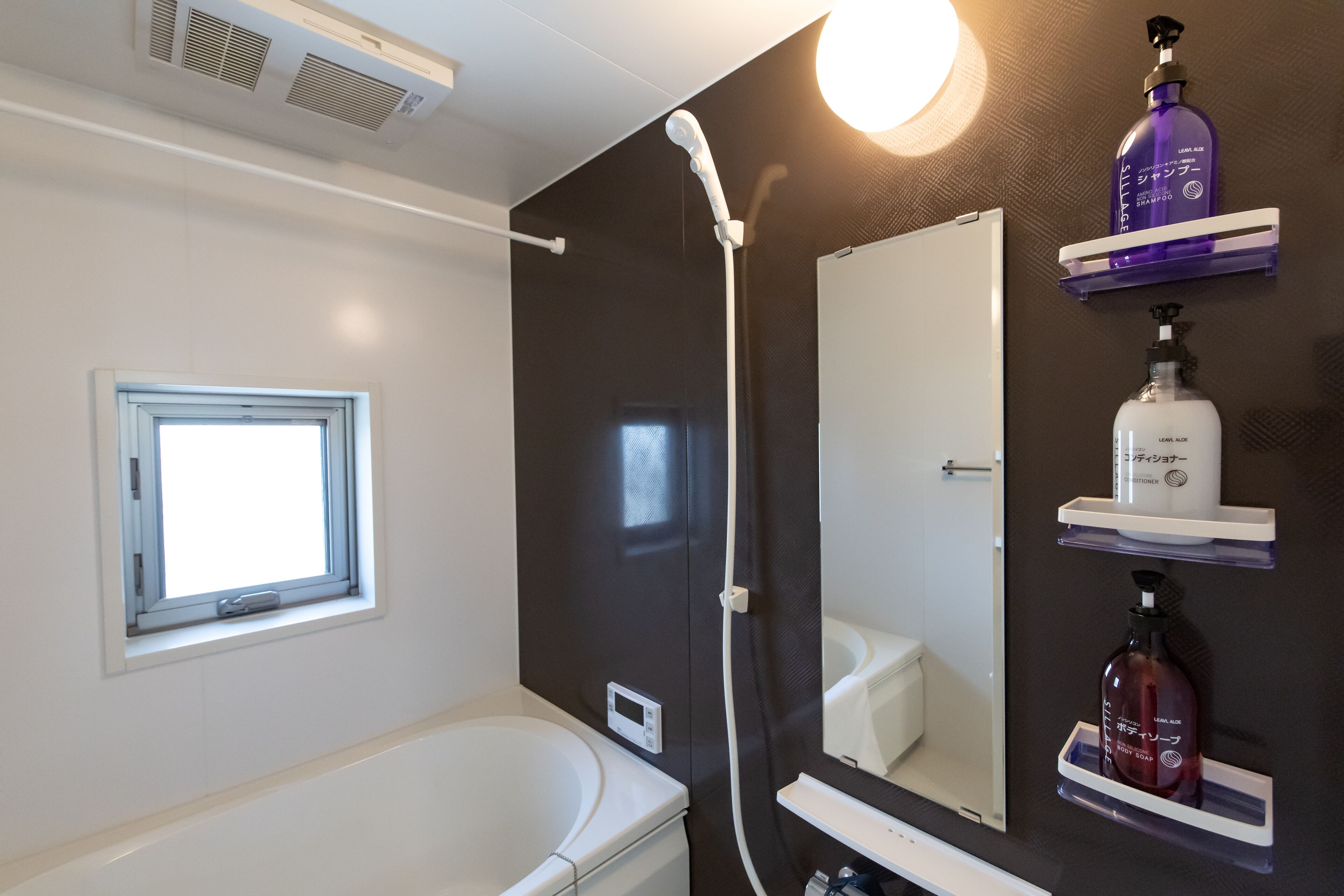 A bathroom with a bathtub, a window, a shower, and shelves with toiletries.