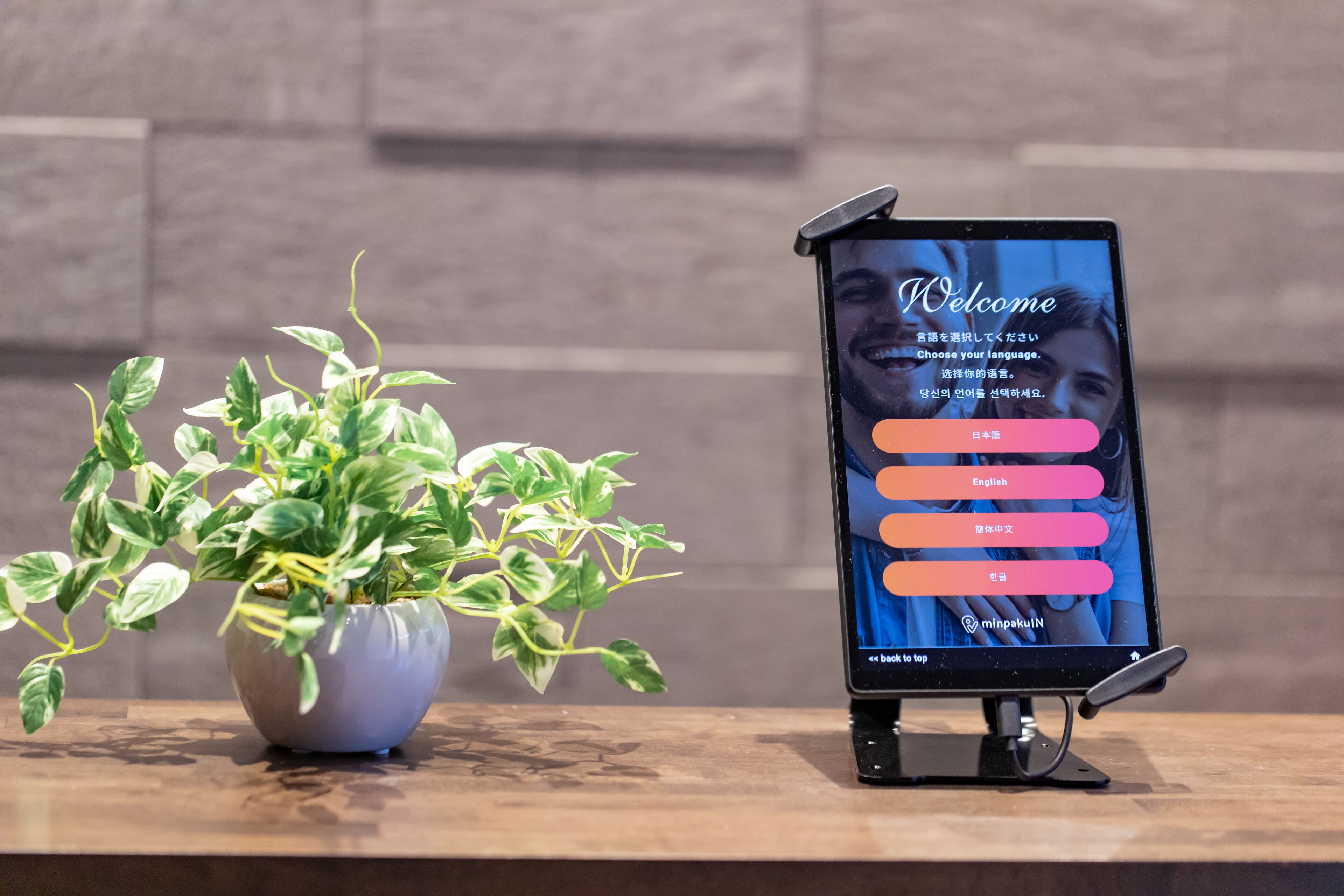 A smartphone on a stand displaying a welcome screen with language selection options.