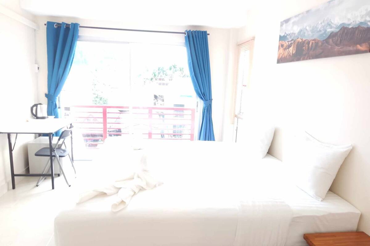 A bedroom with a bed, a desk, and a chair.