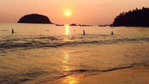 A sunset over a calm sea with boats and people in the water. - LaXenia (Karon)