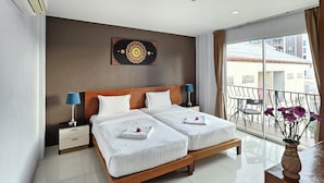 A hotel room with a large bed, two bedside tables, a nightstand, a decorative wall piece, and a balcony with a view of buildings. - LaXenia (Karon)