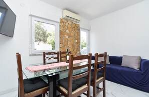 A dining area with a table, chairs, and a stone wall. - Apartment 2221/66969 (Istria - Medulin), 900m from the beach (Medulin)