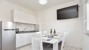 A modern kitchen with white cabinets, a built-in oven, and a flat-screen TV mounted on the wall.