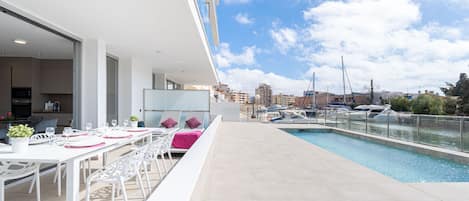 A modern outdoor dining area with a pool and marina view.