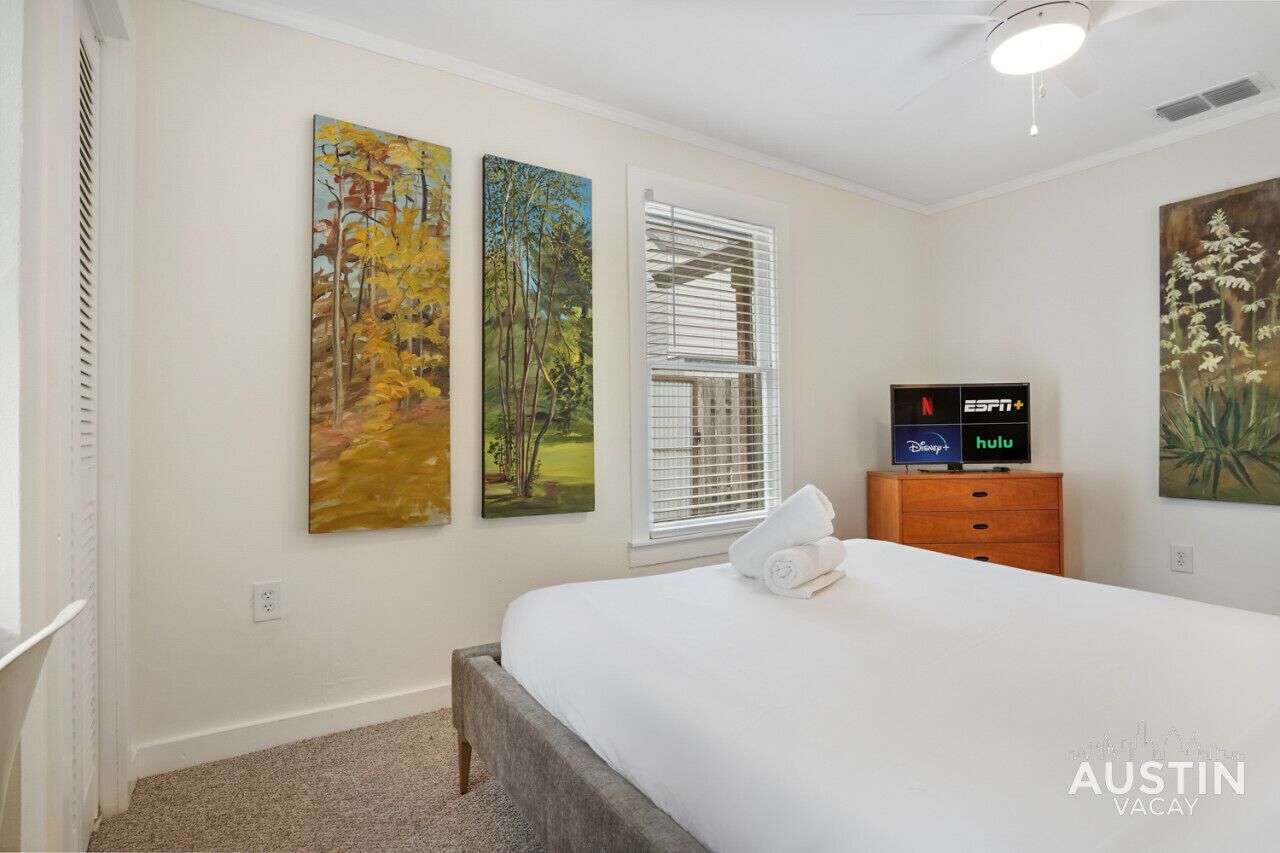 Een slaapkamer met een bed, een dressoir en een televisie waarop ESPN+ en Hulu te zien is.