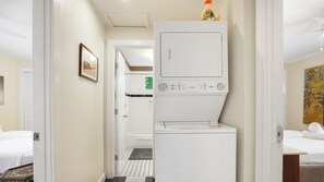 Habitaci ón de hotel con lavadora, una cama, una mesita y un cuadro en la pared.