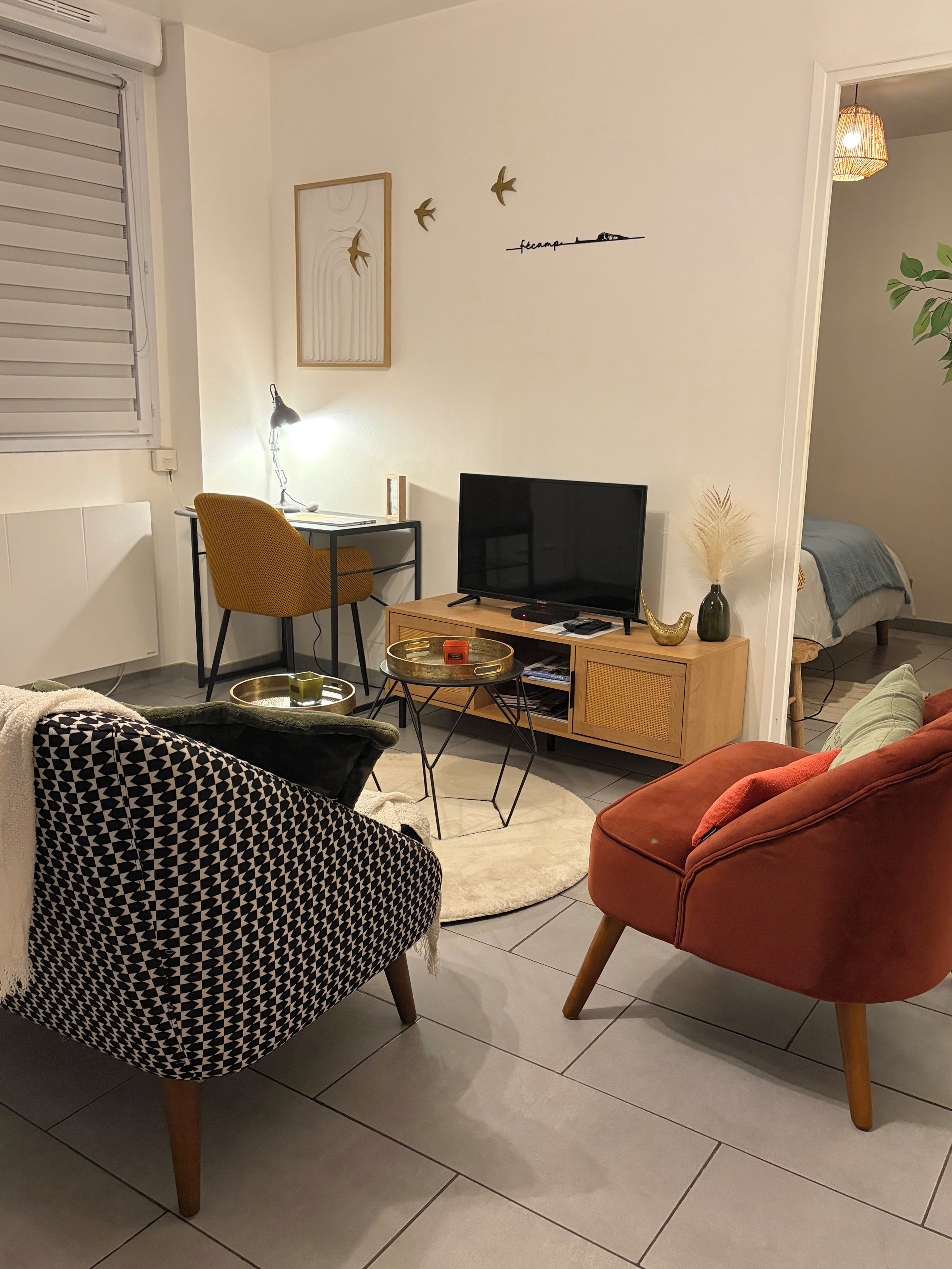 Een woonkamer met een bank, een rode stoel, een televisie, een salontafel en een kast.