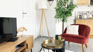 Ein modernes Wohnzimmer mit Fernseher, Holzunterhaltungseinheit, rotem Sofa und einer kleinen Essecke.