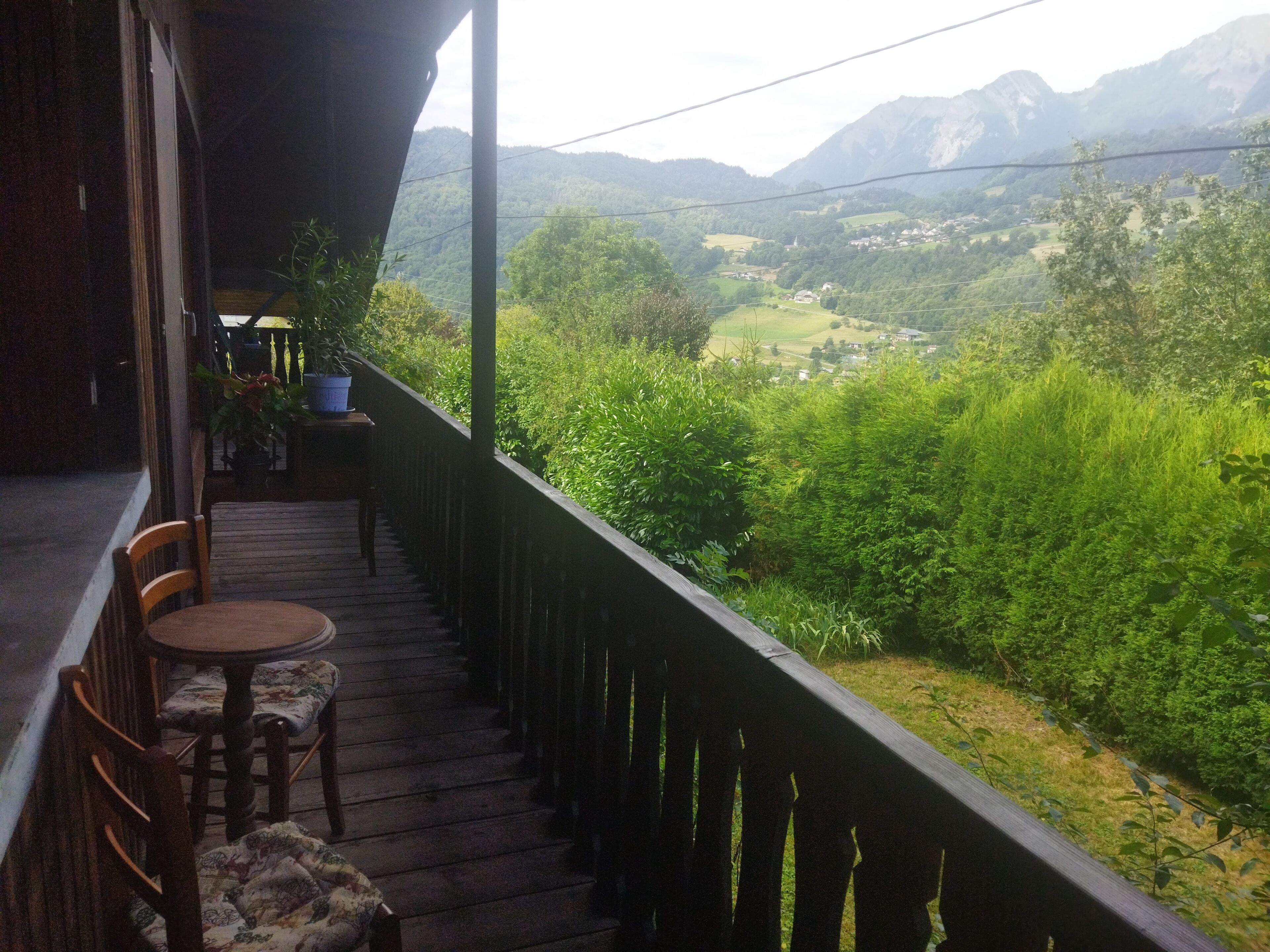 A balcony with a wooden railing, a table, and two chairs.