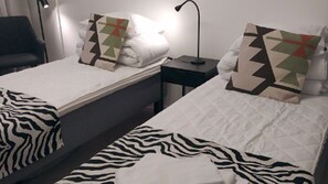 Doble habitación con dos camas, cada una con una manta de estampado de cebra y una almohada geométrica.