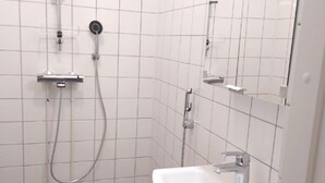 A bathroom with a shower, a sink, and a mirror. - Kuukkeli Sodankylä Apartments (Sodankyla)