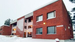 A multi-story brick building with large windows and a sign indicating it is a hotel. - Kuukkeli Sodankylä Apartments (Sodankyla)