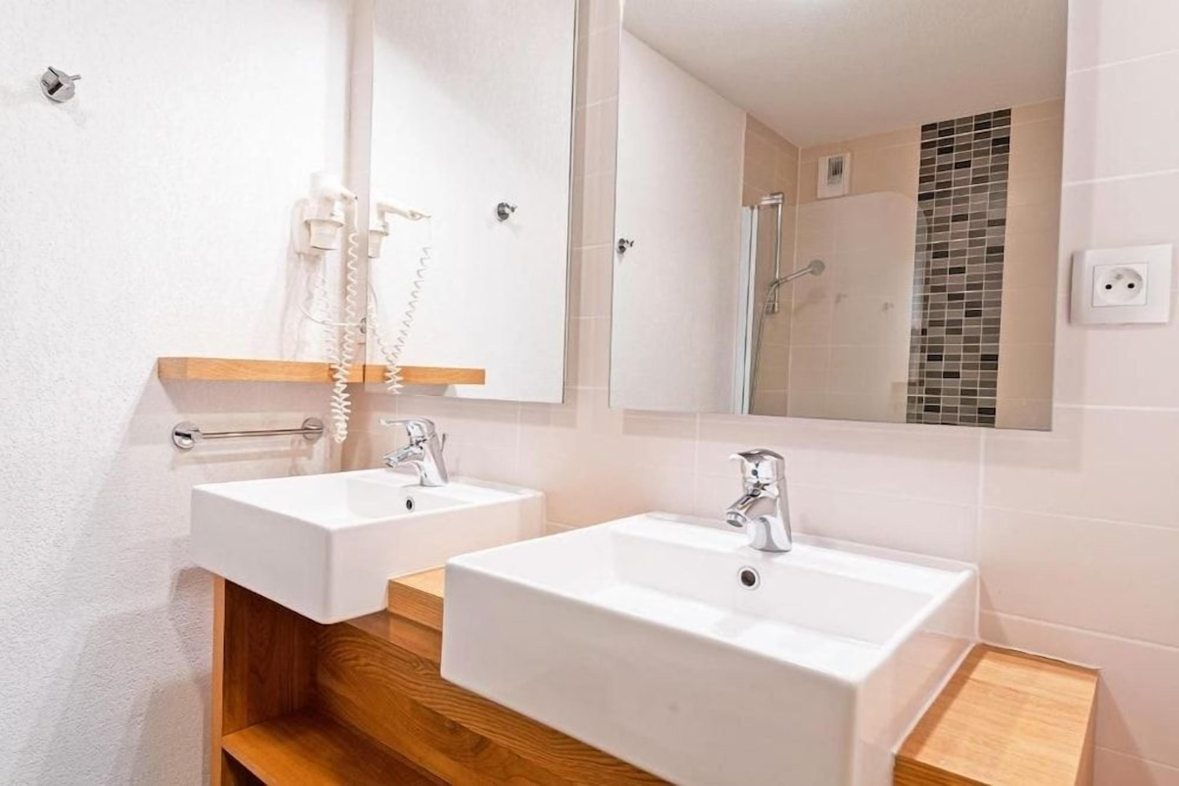 Un baño con dos lavabos, un espejo y una ducha.