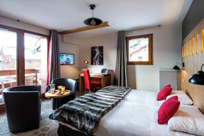 Quarto de hotel com cama, escrivaninha, cadeira, pequena mesa com café da manhã e televisão.