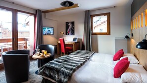 Habitación de hotel con cama, escritorio, silla, una mesita con desayuno y televisor.