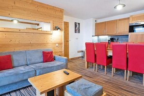 Un espacio de estar moderno con un sofá, una mesa y sillas rojas.