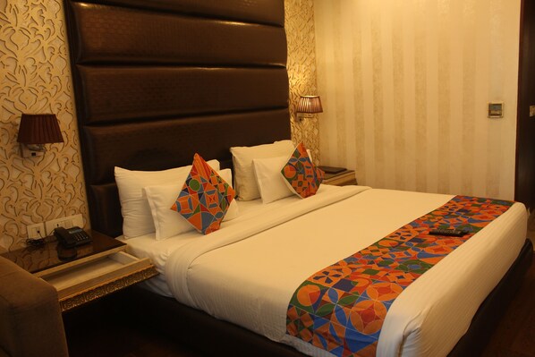 A hotel room with a large bed, a bedside table with a lamp, a telephone, and a decorative pillow. - THE J K Hotel C R Park (New Delhi)