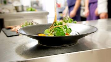A black bowl on a stainless steel counter with a salad.