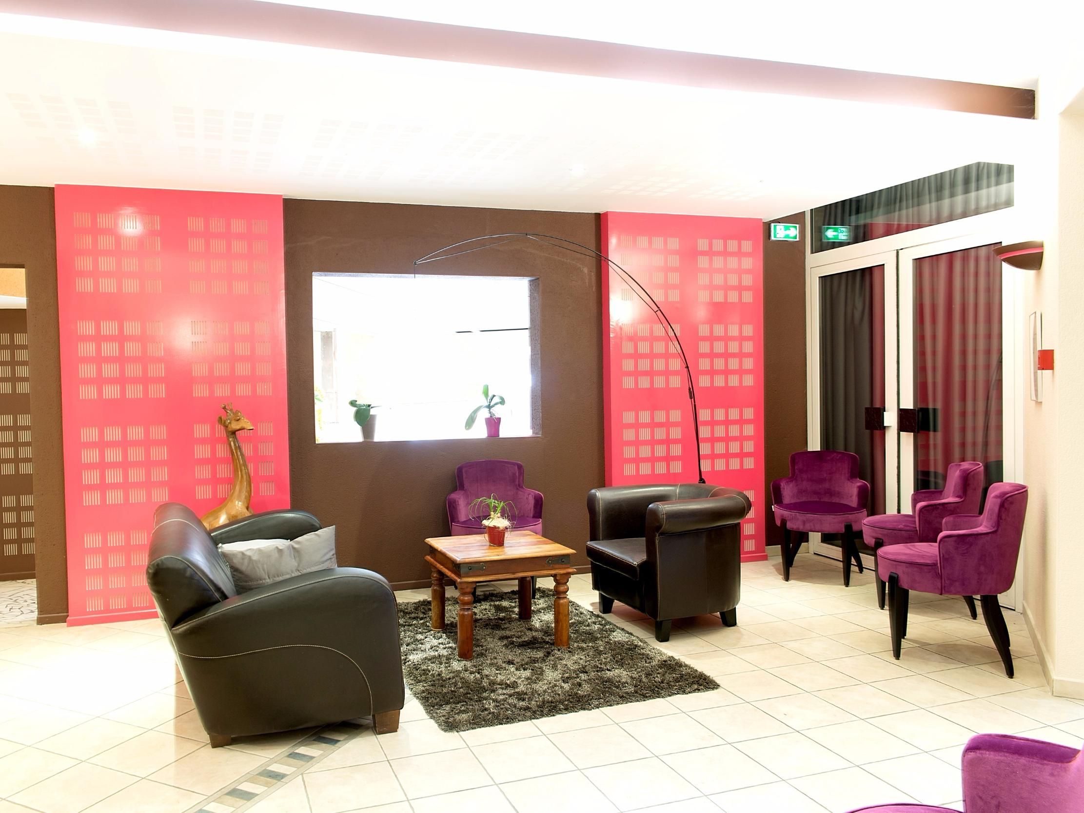 Eine Lobby mit einer Couch, Sesseln, einem Tisch, einer Stehlampe und einem großen Fenster.