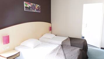 A hotel room with a bed, bedside tables, a wall-mounted picture, and a door.