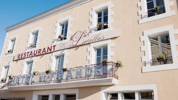 A building with a sign reading 'RESTAURANT Le Lucullus' and 'HOTEL DE FRANCE' indicating a French establishment.