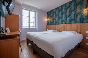 Un dormitorio con una cama doble, un escritorio, una silla, un ventanal y una pared con diseño.